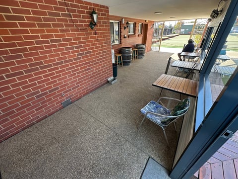 Interior of a brick building with seating area, desks along the wall, and glass doors opening to an outdoor patio area